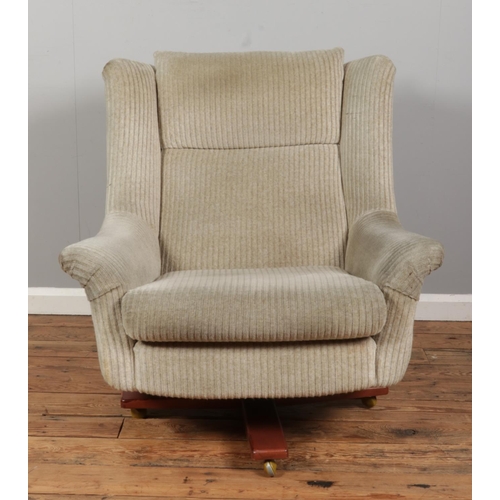 551 - A Mid-Century G-Plan upholstered swivel chain on four point base, raised on casters.