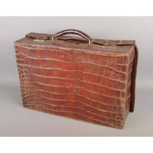 60 - An early 20th century crocodile skin suitcase, size W47 x D32 x H13cm.