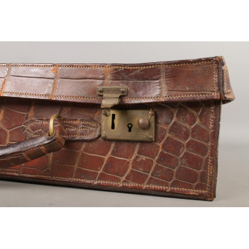 60 - An early 20th century crocodile skin suitcase, size W47 x D32 x H13cm.