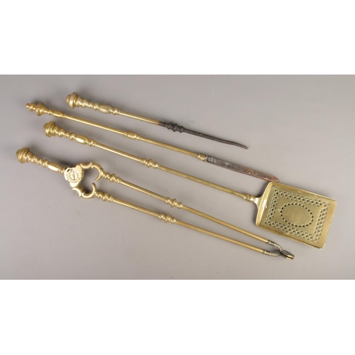 64 - A brass fireside companion set to include coal tongs, pokers and shovel.