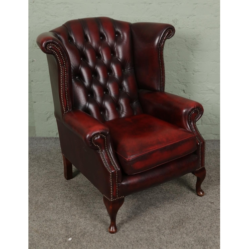 382 - A deep buttoned and studded Chesterfield Wingback armchair, in oxblood red leather.

Hx103cm
Wx90cm
... 