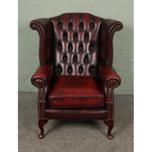 382 - A deep buttoned and studded Chesterfield Wingback armchair, in oxblood red leather.

Hx103cm
Wx90cm
... 