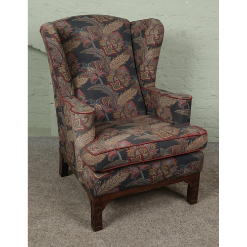 395 - A wing back armchair in the Chippendale style. With floral upholstery and mahogany supports.

Hx110c... 