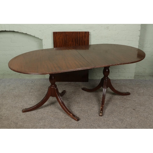 398 - A Regency style twin twin pedestal dining table on turned columns with tripod splayed supports, come... 