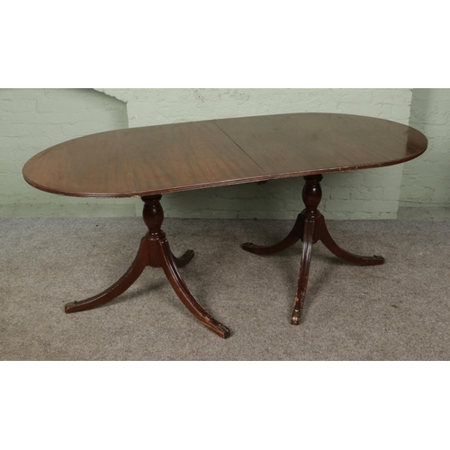 398 - A Regency style twin twin pedestal dining table on turned columns with tripod splayed supports, come... 