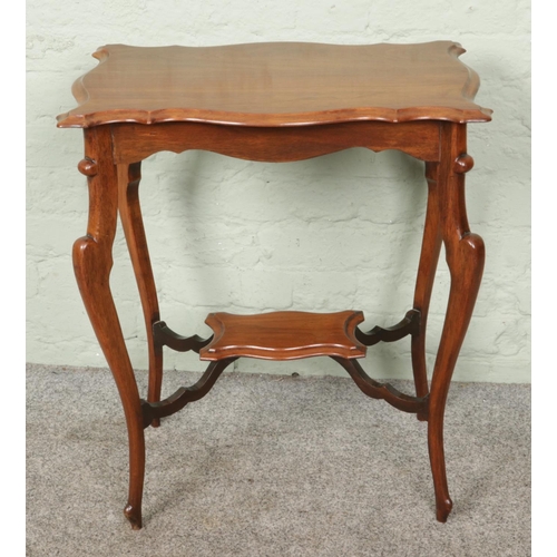 400 - An antique Edwardian two-tiered mahogany occasional table, featuring curved shelves and finely carve... 