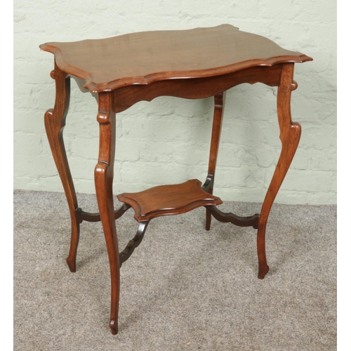 400 - An antique Edwardian two-tiered mahogany occasional table, featuring curved shelves and finely carve... 