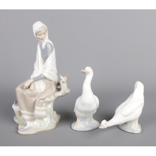 64 - A Lladro ceramic figure depicting a girl with bird on branch along with two Nao by Lladro geese.