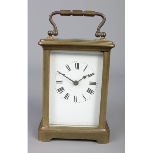 412 - A brass carriage clock with bevelled glass panels, open escapement and Roman Numeral dial.