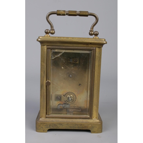 412 - A brass carriage clock with bevelled glass panels, open escapement and Roman Numeral dial.