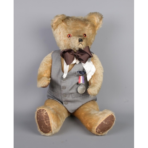 53 - A large antique teddy bear with waist coat and attached a 1937 medal of 