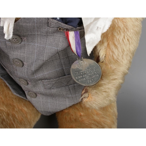 53 - A large antique teddy bear with waist coat and attached a 1937 medal of 