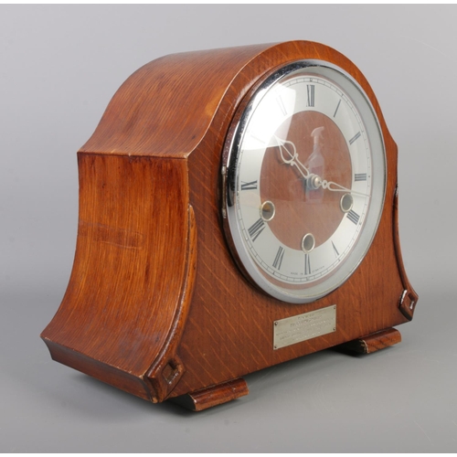 49 - A dome top Smiths Enfield mantle clock, with Roman Numeral dial and bearing presentation plaque to f... 