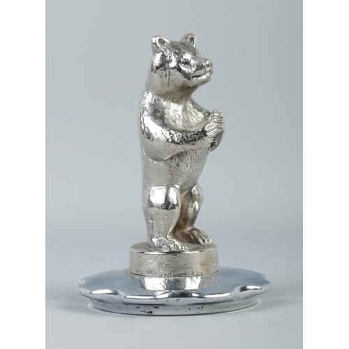 26 - A white metal hood/car mascot modelled as a standing bear. Stamped Copyright AEL (A.E. LeJeune) to b... 