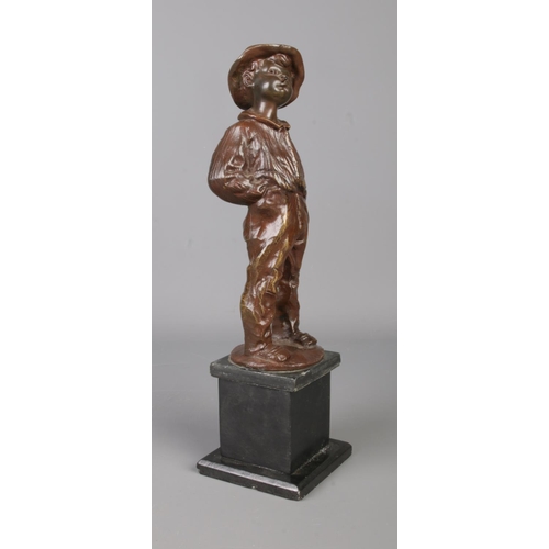 32 - A bronze sculpture of a young boy raised on a square slate plinth. Modelled smoking a cigar, stood w... 