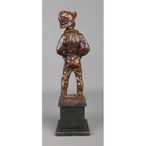 32 - A bronze sculpture of a young boy raised on a square slate plinth. Modelled smoking a cigar, stood w... 