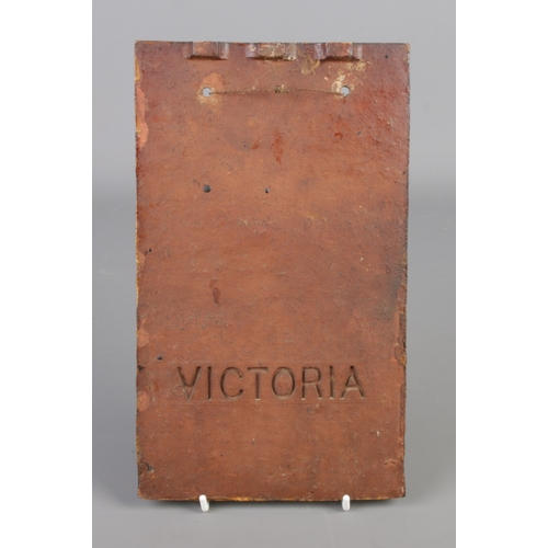 290 - A hand painted terracotta plaque. Decorated with a landscape scene and cottage. Impressed Victoria t... 