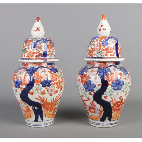 270 - A pair of Chinese lidded vases, decorated with Prunus blossom in blues and oranges, with pointed fin... 