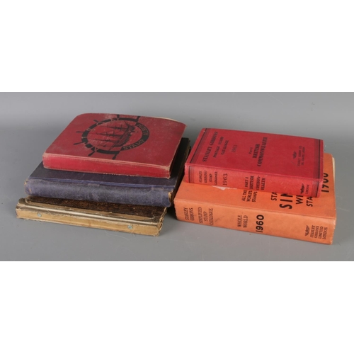 165 - A collection of three vintage world stamp albums with two Stanley Gibbons catalogues (1960/1963). St... 