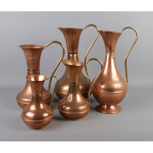 22 - A set of five graduated copper jugs with brass handles