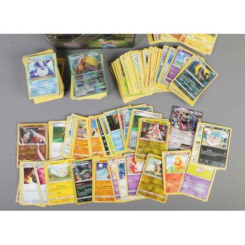 51 - A tin of assorted Pokemon trading cards to include shiny examples such as Rayquaza, energy cards, Pi... 