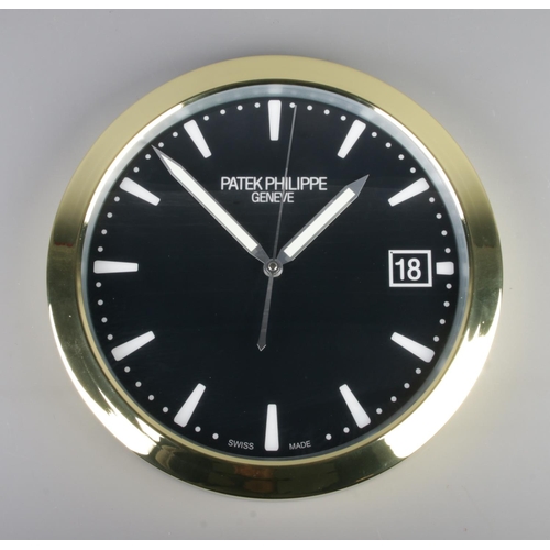 381 - A Patek Philippe watch style wall clock, featuring a gold bezel and black dial featuring baton marke... 