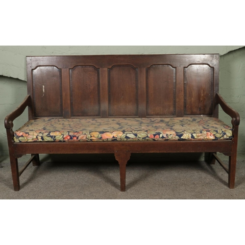 601 - An 18th century oak settle or hall bench with moulded cresting rail over five fielded panelled back.... 
