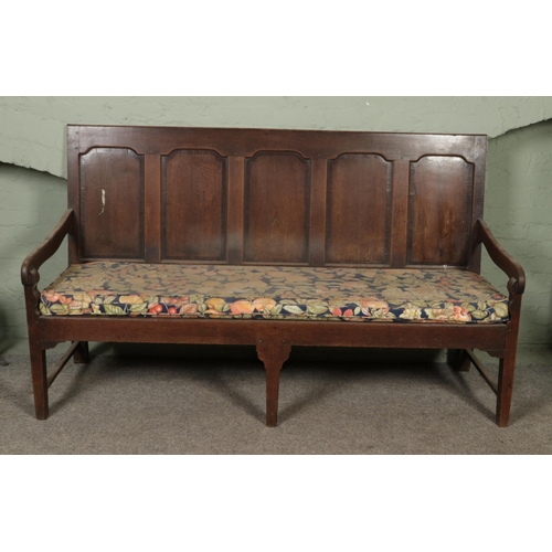 601 - An 18th century oak settle or hall bench with moulded cresting rail over five fielded panelled back.... 
