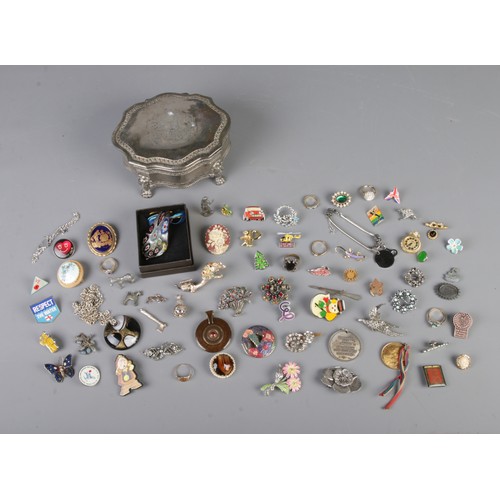 112 - A silver plated jewellery box with contents of assorted costume jewellery. To include Queen's Own Ca... 