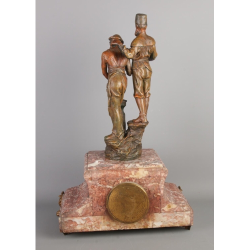 32 - A red marble mantel clock topped with spelter sculpture figures depicting a traditional blacksmithin... 