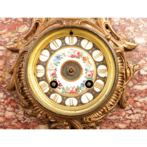 32 - A red marble mantel clock topped with spelter sculpture figures depicting a traditional blacksmithin... 