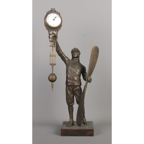 A decorative bronze aviator themed swinging clock, with Arabic numerals and "J" symbol on dial, possibly made by Junghans Germany, running, size W17 x D13 x H40cm.