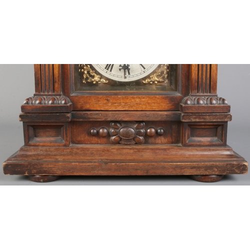34 - An antique German Junghans carved oak mantel clock, featuring deep relief carvings, circular finial ... 