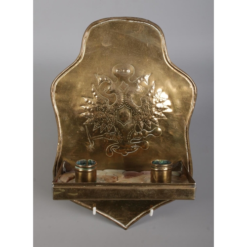 128 - A pair of brass twin candle wall sconces, both decorated with heraldic crests. Height 30cm.