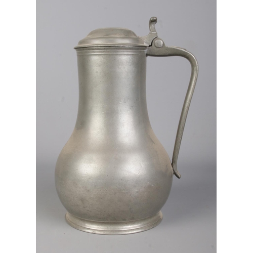 129 - An antique pewter tankard. With scrolled handle and hinged lid. Touch marks to base. Height 26cm.