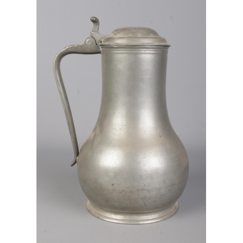 129 - An antique pewter tankard. With scrolled handle and hinged lid. Touch marks to base. Height 26cm.