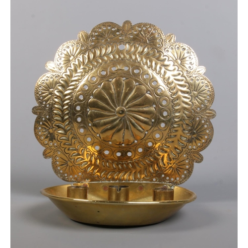 131 - An 18th century brass candleholder. With three candle sockets and repousse and punchwork decoration ... 