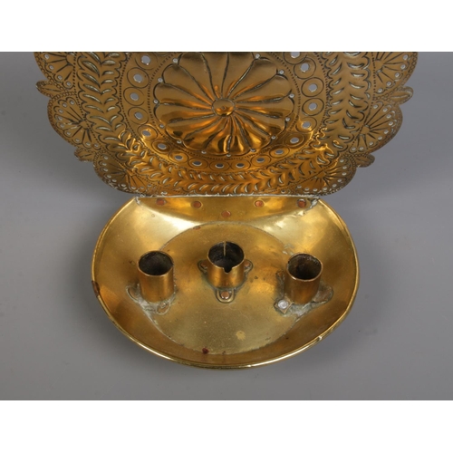 131 - An 18th century brass candleholder. With three candle sockets and repousse and punchwork decoration ... 