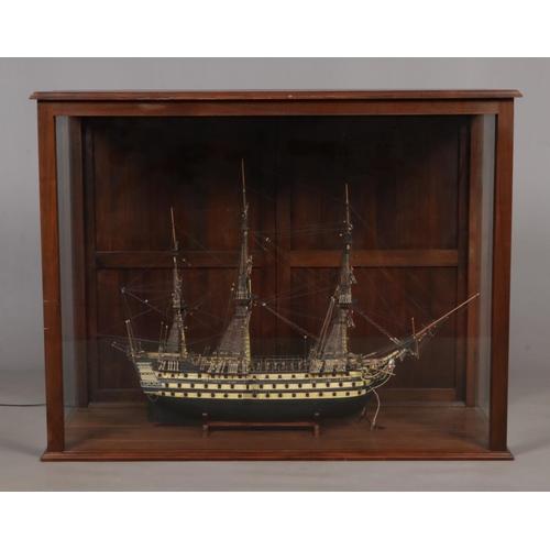 140 - A large hand built model of a war ship, based on HMS Victory, encased within a mahogany and glass il... 