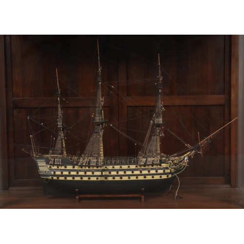 140 - A large hand built model of a war ship, based on HMS Victory, encased within a mahogany and glass il... 