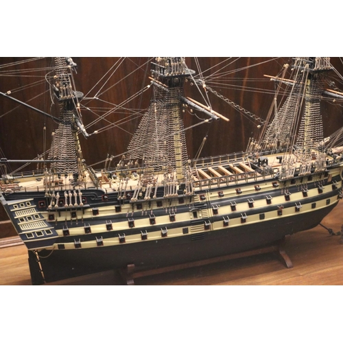 140 - A large hand built model of a war ship, based on HMS Victory, encased within a mahogany and glass il... 
