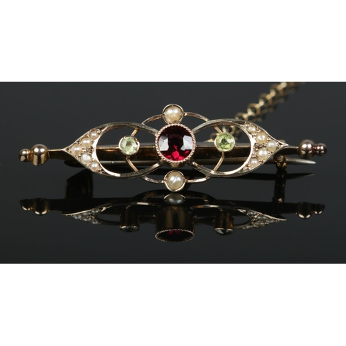 193 - A 9ct yellow gold garnet, peridot and seed pearl brooch. Length 4.5cm. 2.37g.