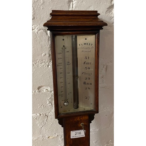 216 - An oak stick barometer by FL West. Length 97cm.
