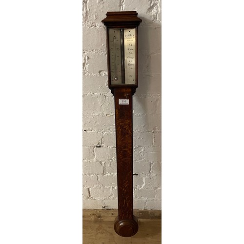 216 - An oak stick barometer by FL West. Length 97cm.