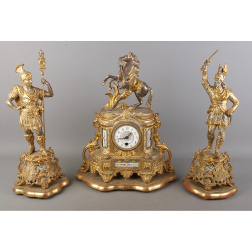 A French spelter and porcelain clock garniture with Marley horse over the clock central to two warriors on matching plinths. Height of clock on stand 43cm.