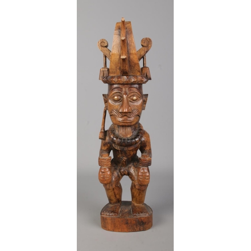 75 - A Nias Island carved wooden statue, ancestor carrying two heads. Height 35.5cm.