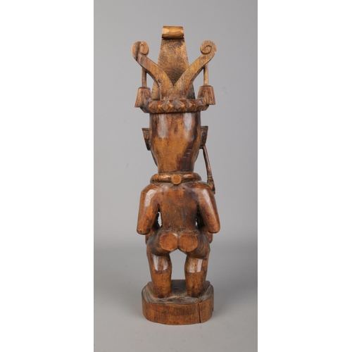 75 - A Nias Island carved wooden statue, ancestor carrying two heads. Height 35.5cm.