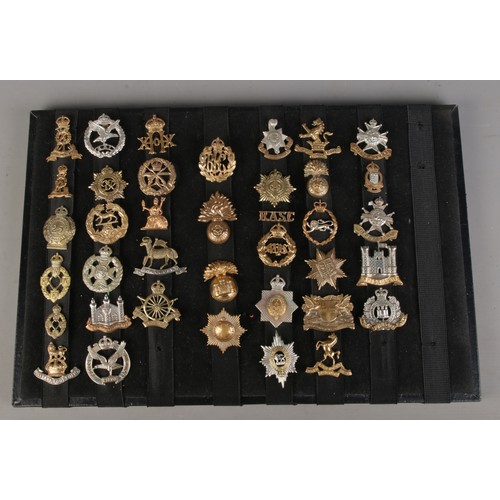 121 - A displayed collection of assorted military cap badges; Glider Pilot Regiment, Small Arms School bad... 