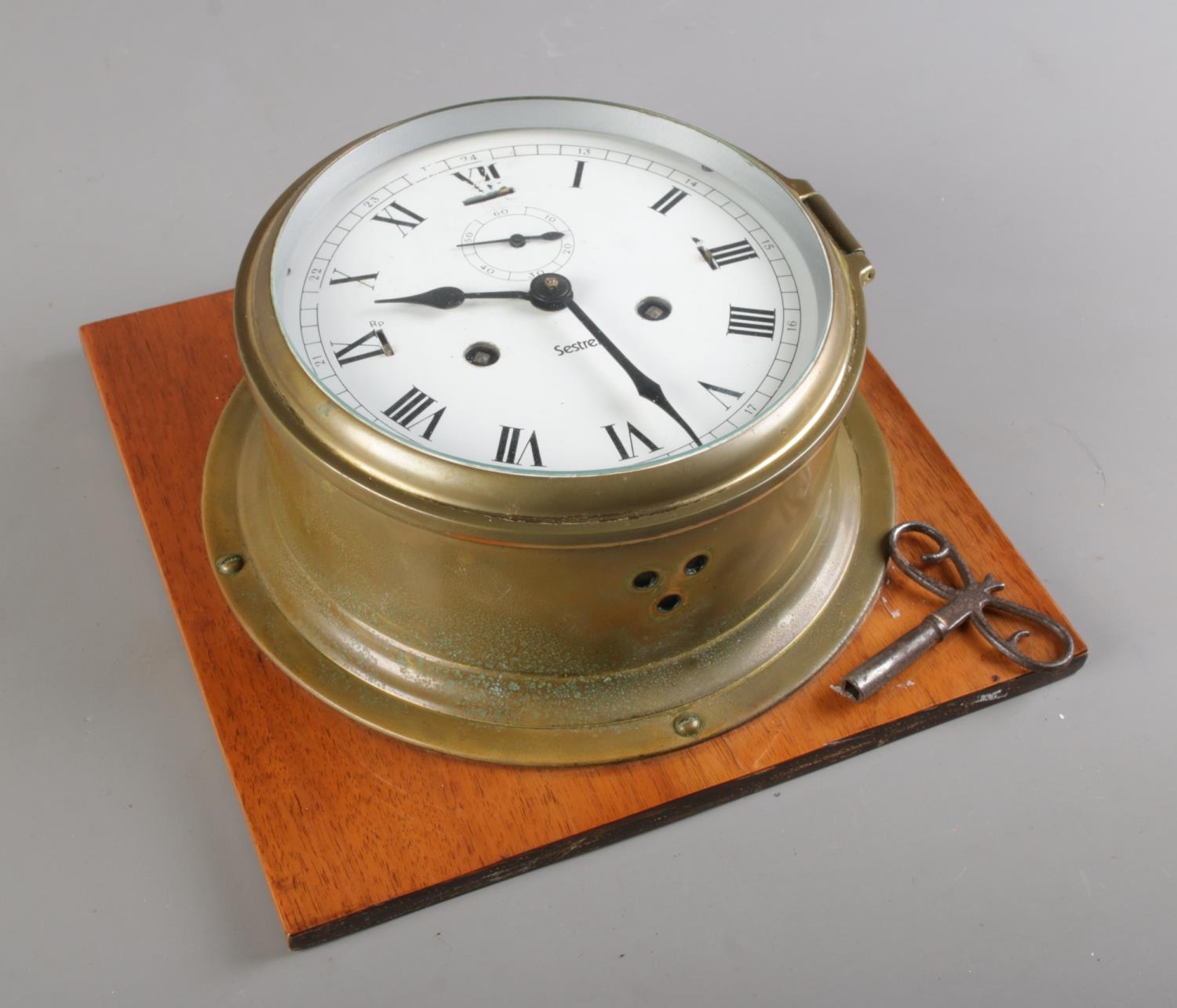 A brass Sestrel ships clock with key; Bearing Roman Numerals. D17cm ...