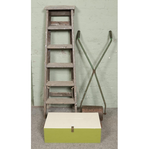 392 - A heavy metal garden roller alongside a bespoke tool box and stepladders.